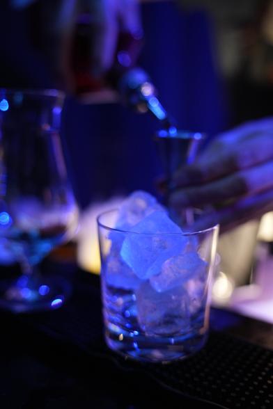 Ein Glas mit Eiswürfeln steht auf der Bar und wartet auf weitere, flüssige Zutaten für einen Drink.
