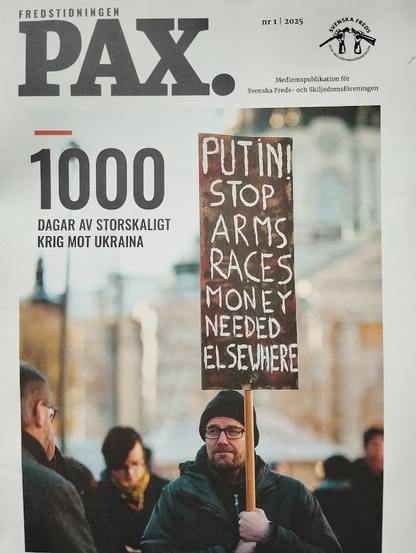 That's the cover of the magazine *Pax*, issue 1 of 2025, published by the Swedish Peace and Arbitration Association. 


Here's a breakdown of the image:

* **Headline:** The large, bold text "PAX." dominates the top of the cover.  Below it, the number "1000" is prominently displayed, indicating 1000 days of large-scale war in Ukraine.  In Swedish, this is written as  "DAGAR AV STORSKALIGT KRIG MOT UKRAINA".

* **Central Image:** The main focus is a photograph of a person holding a hand-painted sign. The sign reads: "PUTIN! STOP ARMS RACES MONEY NEEDED ELSEWHERE." This captures the anti-war sentiment and the call for redirection of resources. The person holding the sign is wearing a dark jacket and a beanie.  They appear serious and focused.

* **Background:** The background of the photo shows a blurred-out city street scene, with other people visible but not in clear focus. It suggests a protest or demonstration environment.

* **Magazine Information:** In the upper right corner are the issue number and year, plus a logo that seems to represent the publisher, which is confirmed in the text below the logo as "Svenska Freds-och Skiljedomsföreningen" (Swedish Peace and Arbitration Association).  The text states that it's a membership publication for this association.

In summary, the cover is a powerful visual statement about the ongoing war in Ukraine, calling for an end to the conflict and advocating for a reallocation of resources away from military spending.