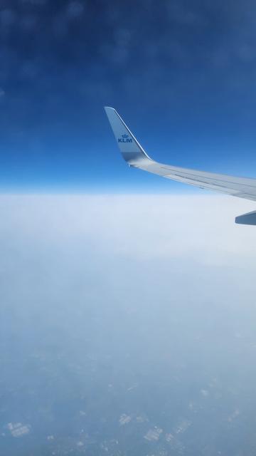 Shot from the window of a KLM plane behind the wing on our way to Prague. Deep blue sky floats above a ground plane of white clouds.