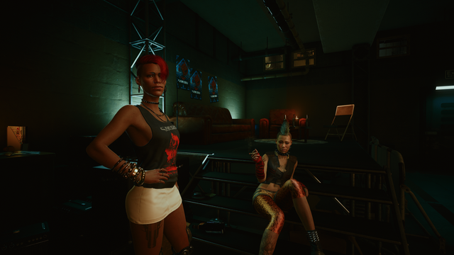 two rock people dressed punk on the back stage. one is dark skinned, wearing tank top and mini skirt. and the other is light skinned and smoking, wearing tights with mini shorts with crop top. both are posing boldly to the camera.