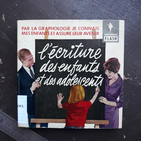 Couverture d'un petit livre carré aux éditions Marabout, collection "Flash". Le titre "L'écriture des enfants et des adolescents" est écrit en cursive à la craie sur un tableau noir par un enfant avec un polo rouge. Ses parents (le père en costume-cravate noir, sa mère en robe violette) placés face au lecteur derrière le tableau, se penchent vers lui. En haut, en lettres capitales rouges : Par la graphologie je connais mes enfants et assure leur avenir".