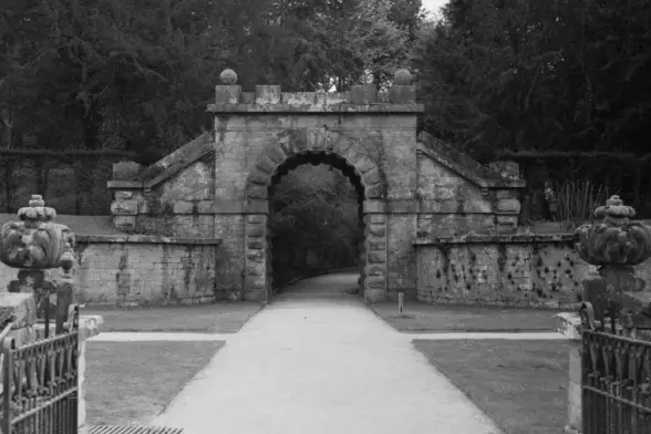 A large stone gatehouse with a path into gardens