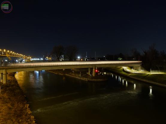 Beleuchteter Fußwegsteg über Fluss bei Nacht