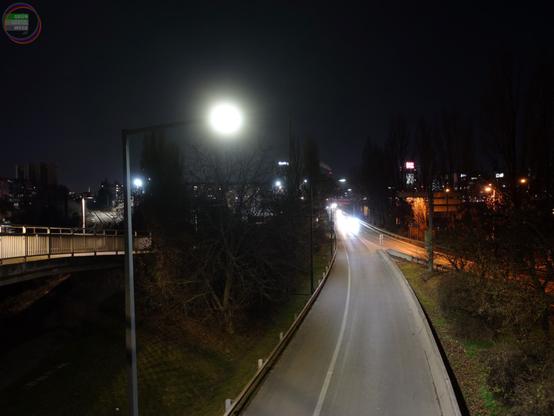 Hochrangige Straße bei Nacht von oben, im Bildrand ein Fußwegsteg
