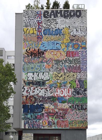 A facade of a large building covered completely with various colorful graffiti