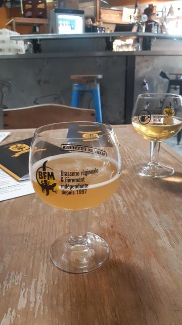 Bauchige Biergläser auf einem Holztisch, dahinter eine Bar.