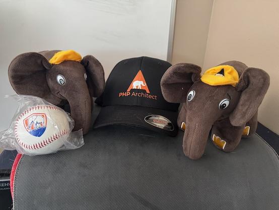 @ Tony PHP Elephant toys between a PHP Architect black baseball hat and a baseball with the PHP Architect elephant logo.