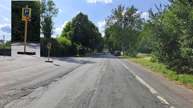 Eine Straße, rechts daneben ein Radweg. Darauf parken Autos. Links ist - recht unscheinbar - die Zufahrt zu einem Parkplatz ausgeschildert (noch einmal im Bild vergrößert dargestellt).
