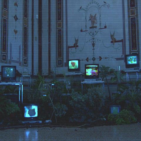 Pablo Bozzi Sleepless Nights cover artwork: A room in blue twilight. Ancient decorations on high walls, white, black. A lot of tables, industry style, different heights, in front, surrounded by flowers. Screens placed on some, displaying images of different colours, abstract but much stronger than the rest of the scenery.