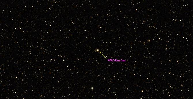 Starry sky with one brighter star in the center labeled by a yellow arrow as V462 Nova Lupi.