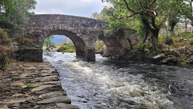 The bridge with two gates from a distance. A stonewall in front along the river.