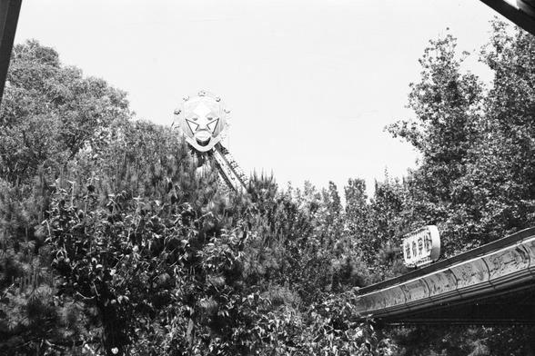 Lucky Lucky SHD 400 (FF)

English alt text:
A photo taken in a lush amusement park with dense green trees. A roller coaster structure peeks through the foliage in the background. In the foreground, there’s an ornate sign with Chinese characters, mounted on a decorative panel with carved patterns.

中文替代文本（Chinese alt text）：
一张拍摄于绿树成荫的游乐园的照片。背景中有过山车结构若隐若现，前景是一块装饰性的告示牌，上面有中文文字，边缘带有精美雕刻。