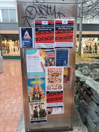 The back of a phone booth covered in posters, mostly of the radical left-wing variety