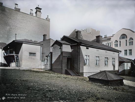 Ritarikatu 6, pihalla sijaitseva asuinrakennus. (1909, Helsingin kaupunginmuseo)

Alkuperäisen valokuvan on ottanut Signe Brander. Tämä kuva on keinotekoisesti väritetty DeOldify-algoritmilla.