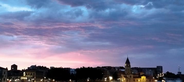 Cielo rozijo en el atardecer sobre la Torre del Reloj y la iglesia de San Pedro de Gijón.