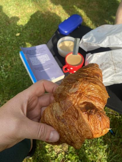 Croissant in meiner Hand überm Frühstückscampingtisch