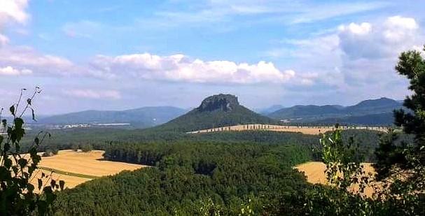 Landschaftsbild: Mittig im Bild: Der Lilienstein in der Sächsischen Schweiz umgeben von Feldern, Wälder und Bergen. Blauer Himmel mit weißen Wolken