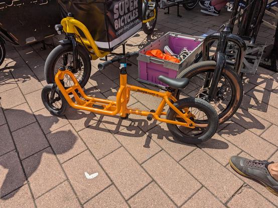 Foto eines kleinen orangenen Lastenrads (Laufrad für kleine Kinder), ohne Box. Aufschrift auf dem Rahmen: "SUPER MIGHTY JR."