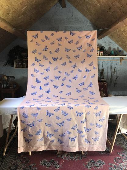 Photo d'un drap rose pastel décoré de papillons bleus suspendu dans mon ancien atelier (mon grenier)