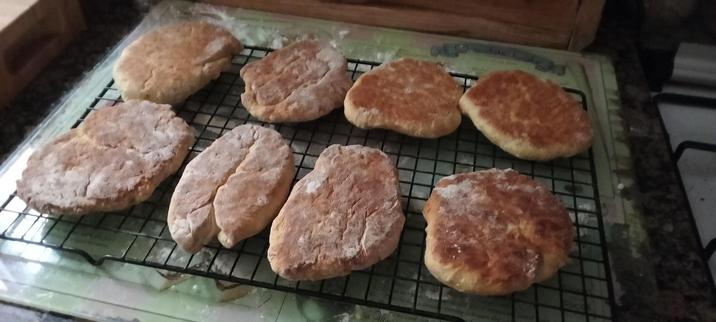 8 freshly baked soda breads cooling on a black cooling rack, a top a glass baking board