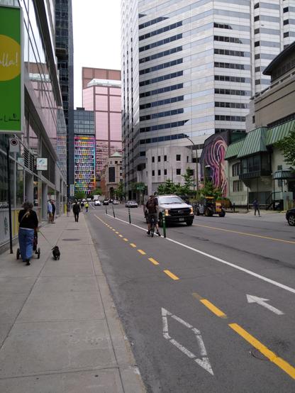 Photo of a street with a bike lane in a city. Tall skyscrapers are visible on all sides.