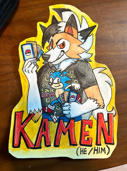 Watercolor painting of an Anthro lycanroc (a wolf-like Pokemon). He is wearing a black thirty with Sonic the Hedgehog on it. He is holding up various cards in his hands. It says “Kamen (He/Him)” on the bottom