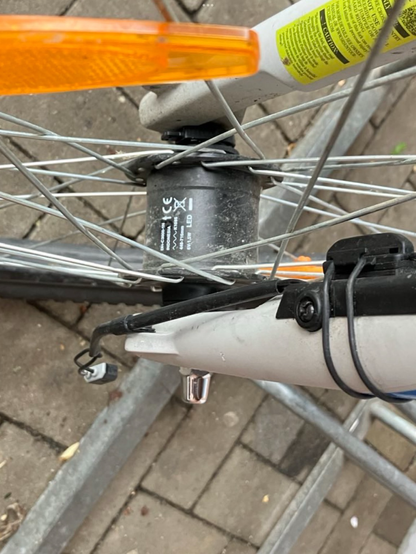 Blick auf ein Vorderrad mit Nabendynamo. Warum hängt denn der Stecker fürs Licht so unmotiviert in der Luft?