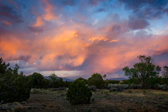 rain clouds over an arroyo lit by the setting sun in Northern New Mexico