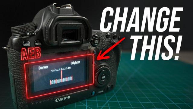 The image shows a Canon DSLR camera with its back panel visible. The camera is positioned on a green cutting mat with a grid pattern. The camera's LCD screen displays an exposure bracketing setting, with the text "Darker" on the left and "Brighter" on the right, indicating the range of exposures from -3.0 to +4.5. The current exposure setting is at -1.3. The letters "AEB" are highlighted in red on the screen, and a red arrow points to the "SET" button below the screen. The text "CHANGE THIS!" is prominently displayed in large white letters on the right side of the image, with a red arrow pointing towards the "SET" button. The camera's body is black, and the buttons and dials are visible, including the "MENU" and "INFO" buttons.

Provided by @altbot, generated privately and locally using Ovis2-8B