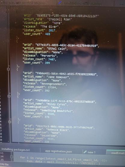An image of JSON objects in a text editor showing artists, release names, listen count and user count. 

The top 3 are:

The Giver - Chappell Roan
Perverts - Ethel Cain
Revengeseekerz - Jane Remover

My face is somewhat visible in the reflection on the laptop screen.