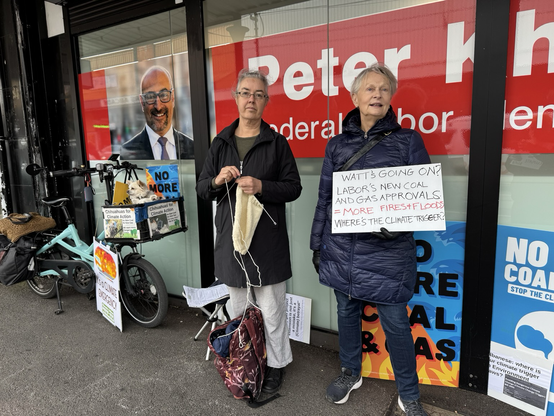 People and 2 chihuahuas standing with climate signs outside MP office