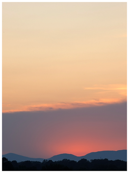 AI-assisted alt text:

	
A serene landscape shows a sunset with an orange and pink sky above distant silhouetted hills and trees. The sun is setting behind the hills, casting a warm glow and subtle gradient from dark blue to peach across the sky.