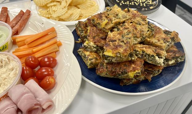 A series of plates loaded with finger food, including potato chips, rolled ham, carrots, cherry tomatoes, dips, and the cheesy spinach frittata from the previous post, now cut up into squares