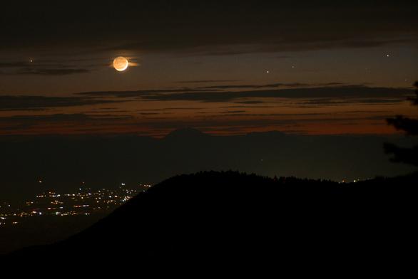 From left to right: Mercury, two-day old crescent moon, and the stars Pollux and Castor of Gemini line up in the evening sky. Below are the lights of La Luz, New Mexico.