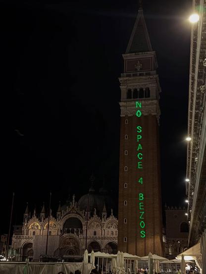 La scritta “NO SPACE FOR BEZOS” proiettata con laser verde sul campanile di piazza San Marco, a Venezia.
