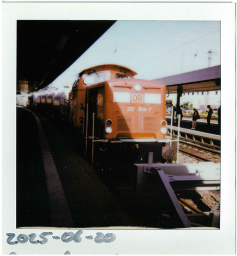 a polaroid picture of a DB diesel locomotive standing in a train station