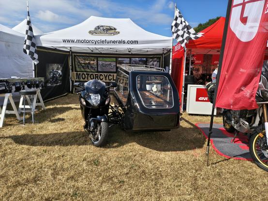 A black motorcycle with a black sidecar, used as a hearse.