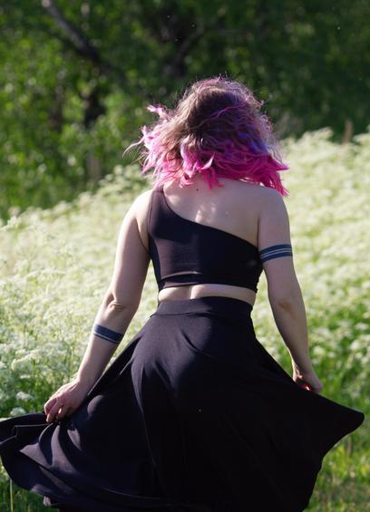 A woman in a skirt and crop top dancing in a meadow