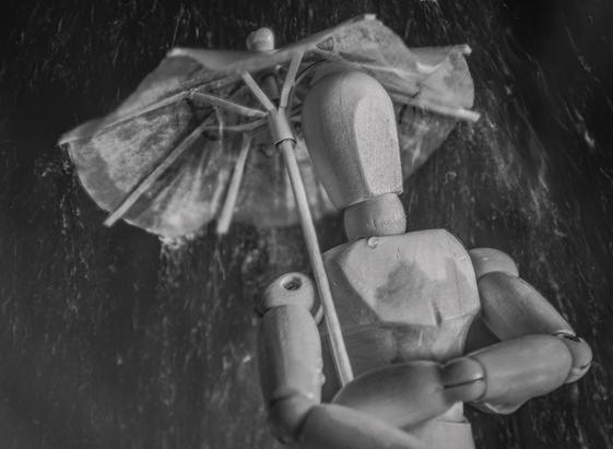 Das Bild zeigt eine melancholische Szene einer Holzpuppe, die sich mit einem Regenschirm im Regen versteckt.

Das Bild ist in Schwarz-Weiß gehalten und zeigt eine detailreiche Darstellung einer hölzernen Künstlerpuppe, die unter einem kleinen, leicht beschädigten Regenschirm steht. Der Regenschirm scheint nicht sehr effektiv zu sein, da Regentropfen auf die Puppe fallen. Die Puppe hat die Arme verschränkt und den Kopf leicht gesenkt, was einen Eindruck von Traurigkeit oder Resignation vermittelt. Der Hintergrund ist unscharf, aber man kann erkennen, dass es stark regnet. Die Atmosphäre ist düster und melancholisch, die Stimmung eher traurig und nachdenklich.  Das Bild wirkt insgesamt sehr still und einsam.  Die Schärfe liegt auf der Puppe und dem Regenschirm, der Hintergrund ist unscharf dargestellt. Die gesamte Komposition suggeriert ein Gefühl von Schutzlosigkeit und Einsamkeit trotz des Versuchs, sich durch den Regenschirm zu schützen.