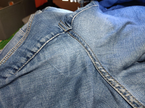 Again, the crotch area of a pair of blue jeans, with no visible damage left. One side is densely filled with stitches, the other side less densely filled, both in a grid-like pattern. It's pretty hard to even notice, it mostly just looks like the rest of the fabric, but rougher.