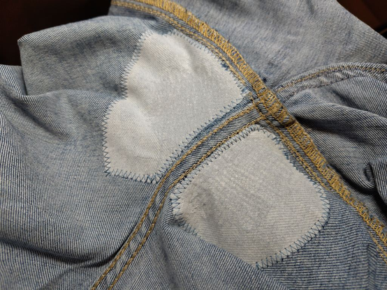The inside of the jeans, with the repaired areas coverid with very thin white cotton, sewn in place with a zig zag stitch.