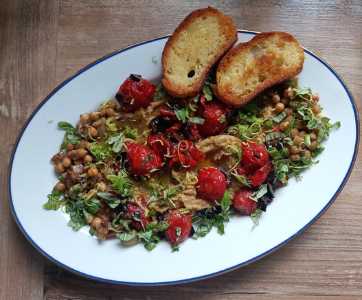 Das fertige Gericht mit 2 Scheiben geröstetem Baguette auf einer Servierpkatte