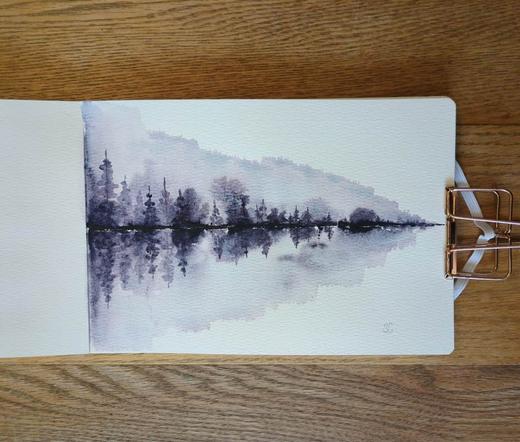 This is a Reflective Atmospheric Watercolor Landscape Painting in landscape orientation in an A5 sketchbook. I used Daniel Smith Moonglow for this art piece because it is made up of three pigments: Veridian, Ultramarine Blue, and Anthraquinoid Red. In masstone the color is a dark smokey cool purple but when it is diluted the blue and red splits out. Along the tree line is Moonglow in masstone then it's diluted above and below the tree line getting bursts of dark and medium value smokey purple; those are diluted further into lighter values and this where the pigment splitting happens. The composition is a horizontally stretched triangle with taller trees on the left getting shorter moving to the right.