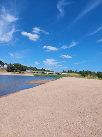 Sois un ciel bleu et légèrement nuageux:
banc de sable, la Loire très  basse et au loin un pont de pierre. Des arbres et des maisons en arrière  plan