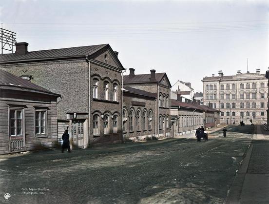 Mariankatu 24, 26, 28. (1907, Helsingin kaupunginmuseo)

Alkuperäisen valokuvan on ottanut Signe Brander. Tämä kuva on keinotekoisesti väritetty DeOldify-algoritmilla.