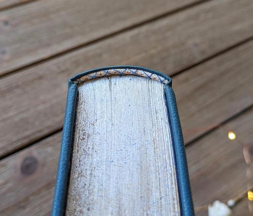 The top edge of a book. The page edges are painted silver and there is a white endband.