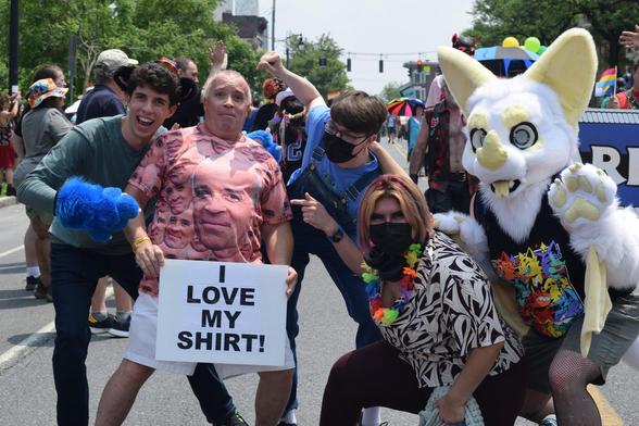 Eufuria members posing with a paradegoer wearing a shirt with his own face on it.