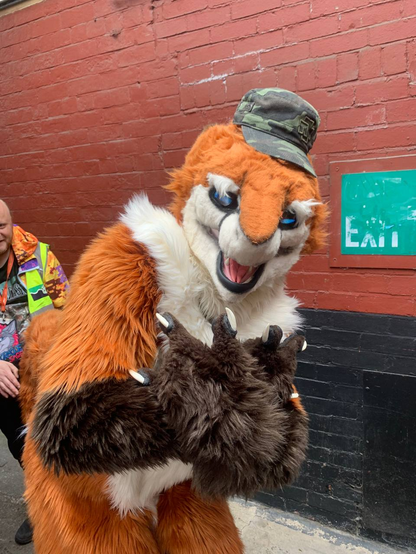 Orange sergal fursuiter throwing gang signs while wearing an army cap