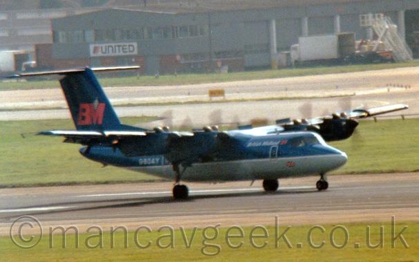 Side view of a high-winged, 4 propellor-engined airliner moving at speed from left to right  along a black runway, with the propellors merely spinning blurs, and flaps extended from the rear of the wings.
The plane is mostly dark blue, with a grey belly, with white "British Midland" titles on the upper forward fuselage, next to a red "BM" logo just behind the cockpit windows.
The white registration "G-BOAY" is on the rear fuselage, while the tail has a larger version of the red "BM" logo.
Green grass lines the sides of the runway in the foreground, with a taxiway and a grey building in the background.