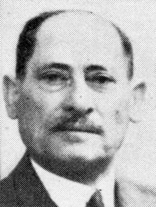 Black and white portrait of a man, wearing a suit and tie, looking slightly to the right of the camera.